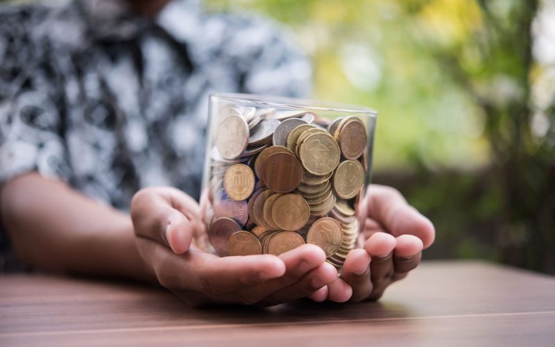 hand-putting-coins-in-jar-with-money-stack-step-g-2021-08-30-23-06-38-utc